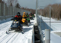 Photo of snowmobiles crossing snow-covered bridge