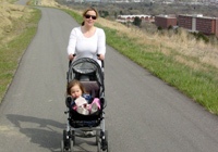 Photo of woman with baby stroller on asphalt trail