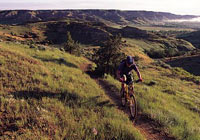 Bicyclist on dirt trail in grassy hills