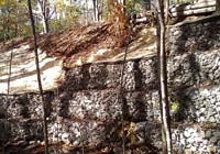 Photo of wire baskets with rocks holding up bank below trail