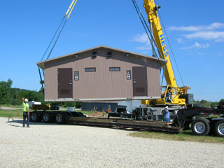Photo of restroom facility being moved by boom truck
