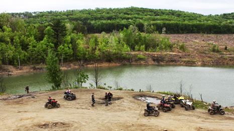 Photo of people on ATVs on a trail next to river