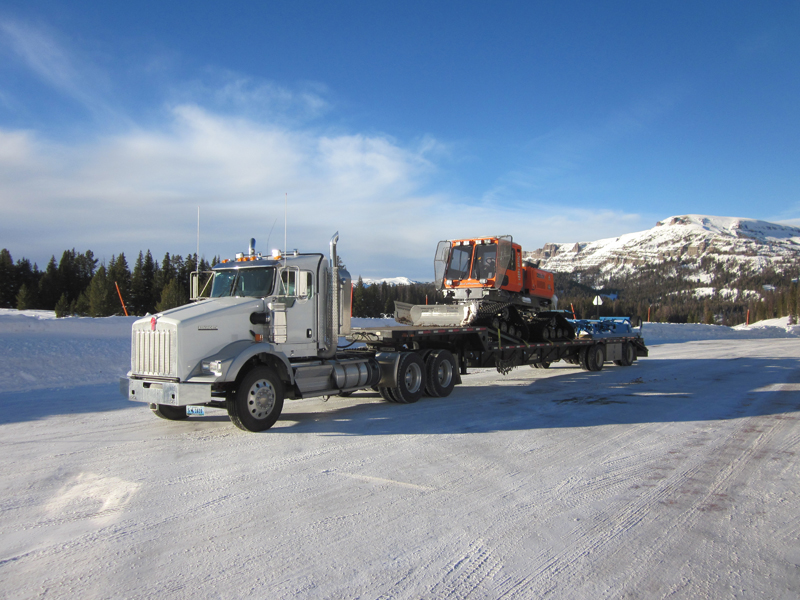 Photo of a trailer truck hauling a snow groomer